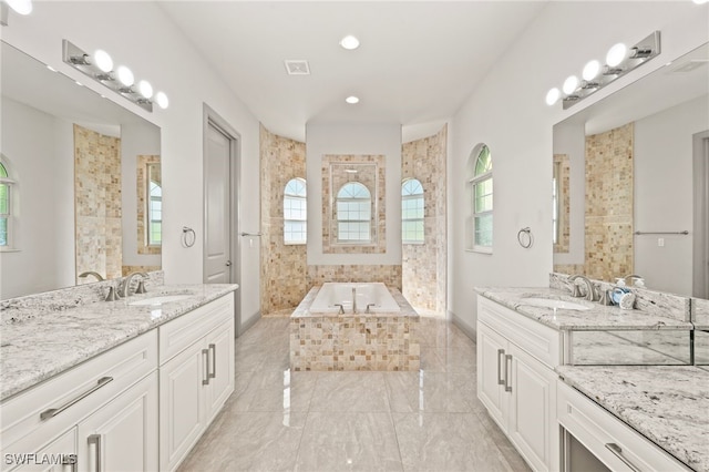 bathroom with vanity and tiled bath