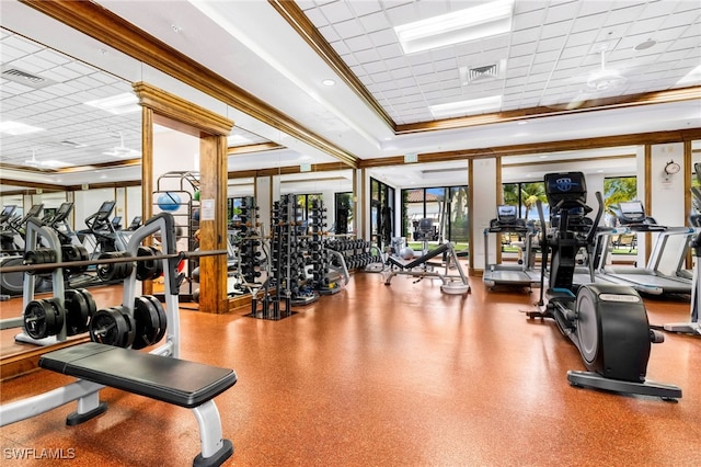 gym featuring a paneled ceiling, ornamental molding, and a raised ceiling