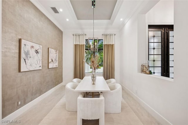 tiled dining room featuring ornamental molding and a tray ceiling