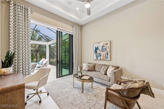 tiled living room with ceiling fan and a raised ceiling