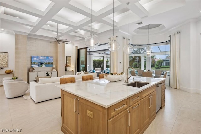 kitchen with ceiling fan with notable chandelier, light stone countertops, pendant lighting, an island with sink, and coffered ceiling