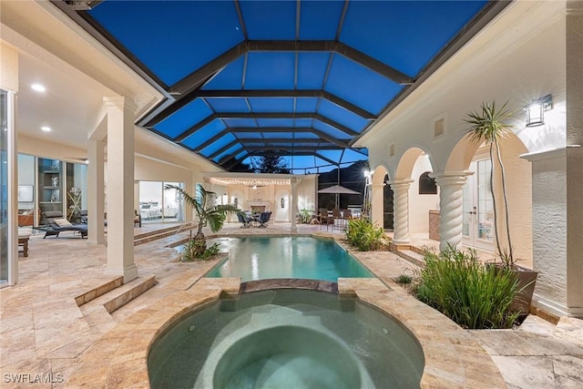 view of swimming pool featuring glass enclosure, an in ground hot tub, and a patio