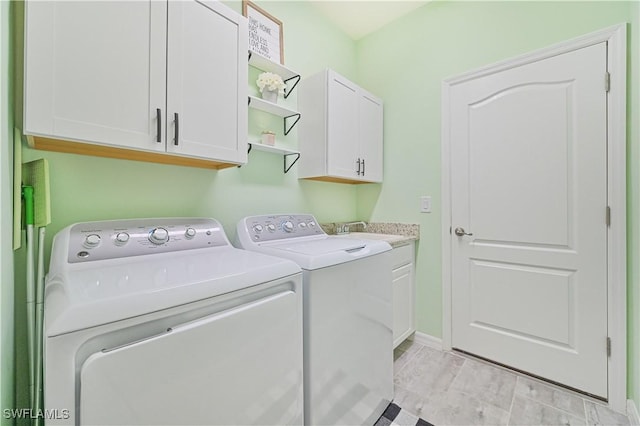 washroom with cabinets, washer and dryer, and sink