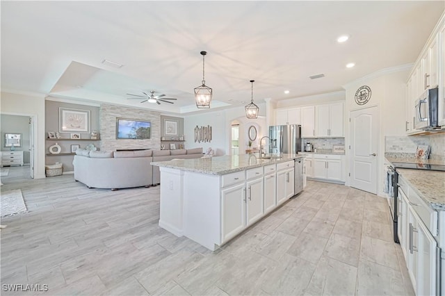 kitchen with white cabinetry, decorative light fixtures, stainless steel appliances, and a center island with sink