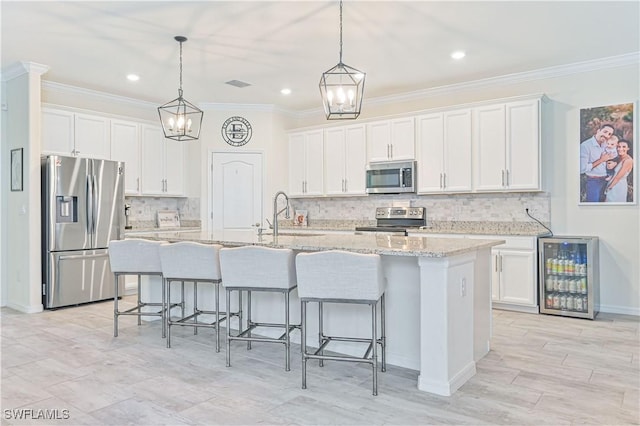 kitchen with sink, white cabinetry, stainless steel appliances, wine cooler, and an island with sink