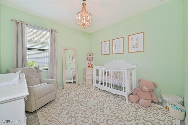 bedroom featuring a nursery area and a chandelier