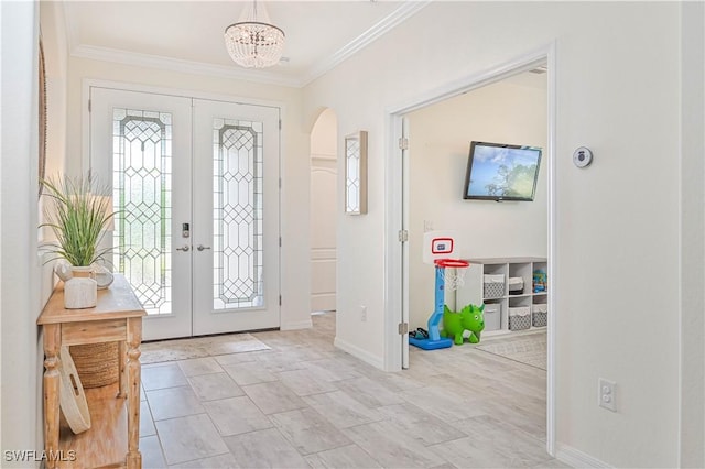 entryway with crown molding, french doors, and a chandelier