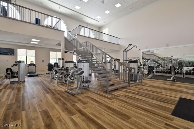 exercise room featuring hardwood / wood-style floors and a towering ceiling