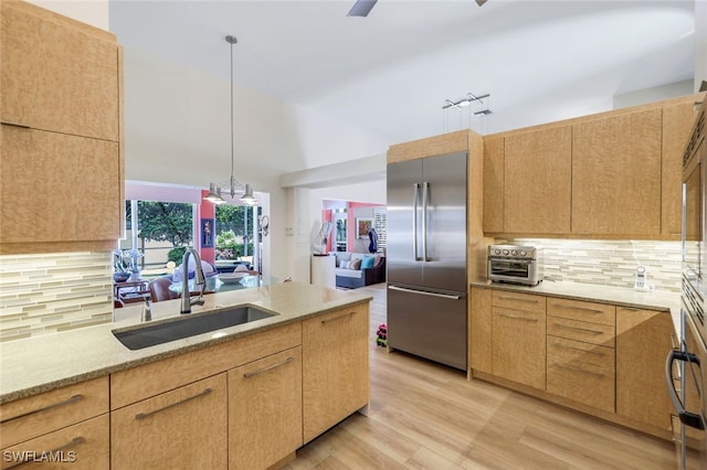 kitchen with pendant lighting, backsplash, built in fridge, sink, and light brown cabinetry