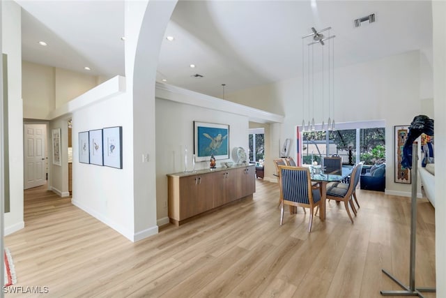 dining room with a towering ceiling and light hardwood / wood-style floors