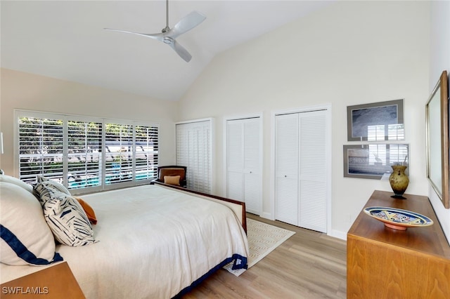 bedroom with lofted ceiling, ceiling fan, hardwood / wood-style floors, and two closets