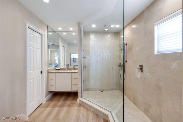 bathroom with vanity, wood-type flooring, and tiled shower