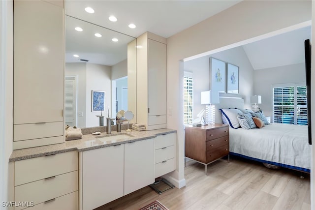 bedroom featuring sink, vaulted ceiling, and light hardwood / wood-style flooring