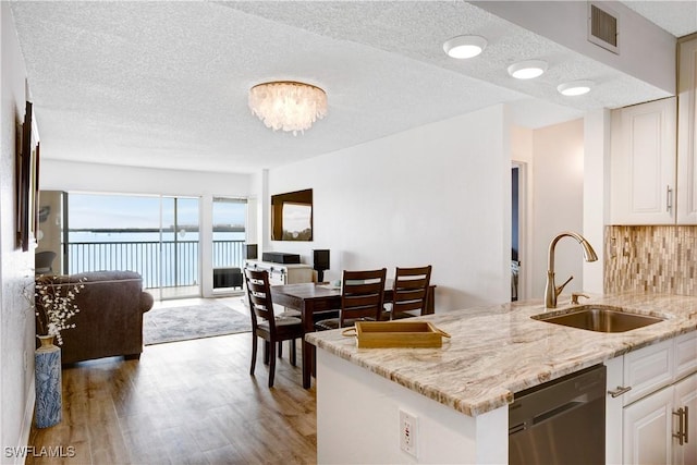 kitchen with white cabinets, dishwasher, light stone counters, and sink