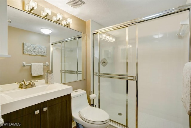 bathroom featuring vanity, a shower with shower door, and toilet