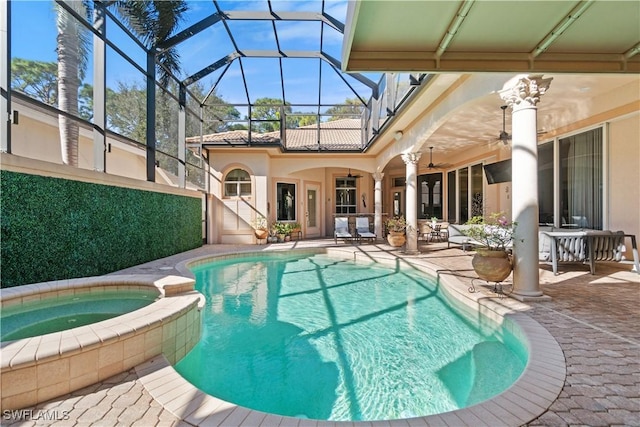 view of pool featuring glass enclosure, ceiling fan, a patio, and an in ground hot tub