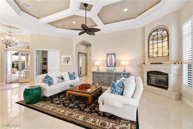 living room with ceiling fan with notable chandelier, light tile patterned flooring, a healthy amount of sunlight, and coffered ceiling