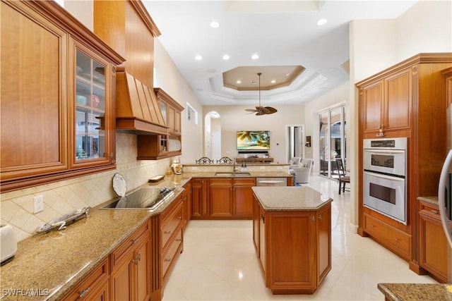 kitchen with kitchen peninsula, light stone counters, sink, and stainless steel appliances