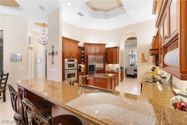 kitchen featuring decorative light fixtures, sink, light stone counters, a notable chandelier, and stainless steel appliances