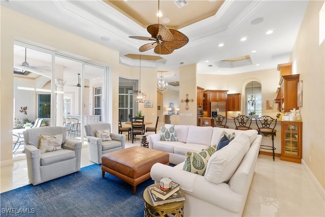 tiled living room with ceiling fan, a high ceiling, ornamental molding, and a raised ceiling