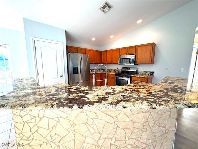 kitchen featuring kitchen peninsula, stainless steel appliances, light stone countertops, and lofted ceiling