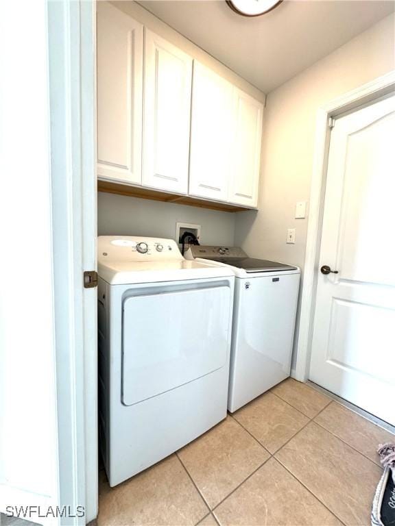 laundry area with washing machine and dryer, light tile patterned floors, and cabinets