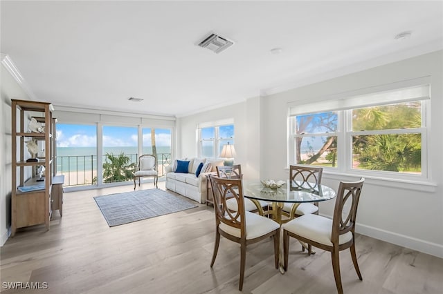 dining area with a water view, light hardwood / wood-style floors, and ornamental molding