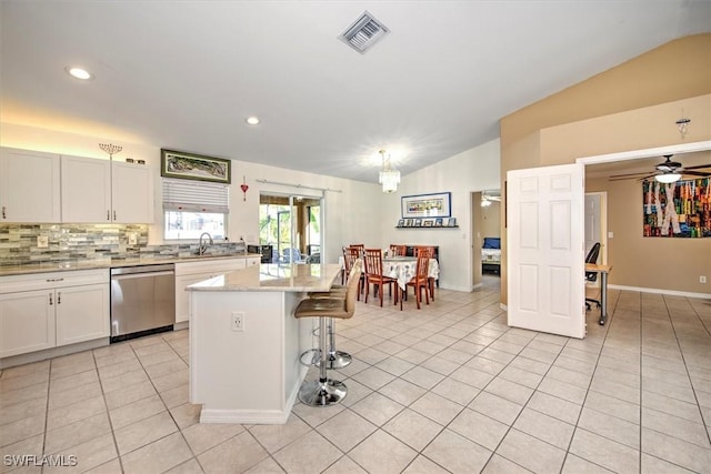 kitchen with dishwasher, a center island, light tile patterned floors, lofted ceiling, and white cabinets