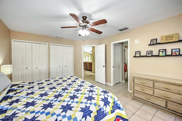 bedroom featuring ceiling fan, multiple closets, and light tile patterned flooring