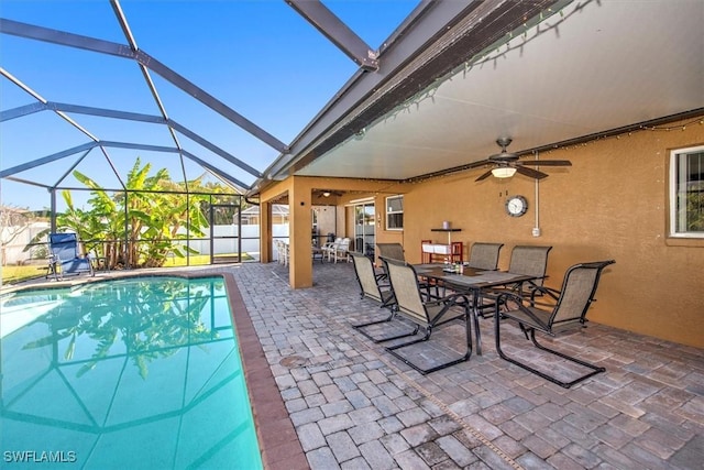 view of pool featuring glass enclosure, ceiling fan, and a patio