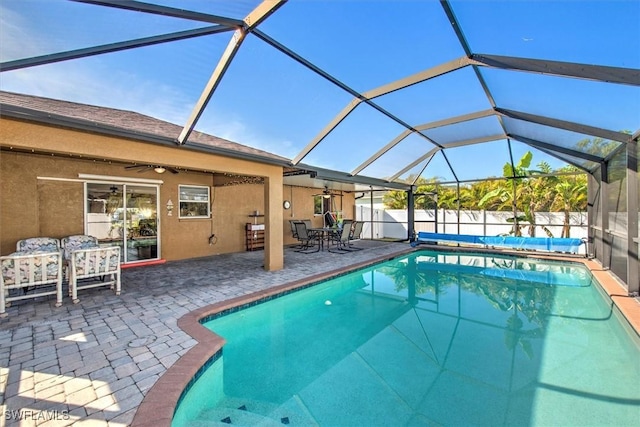 view of pool featuring a patio, glass enclosure, and ceiling fan