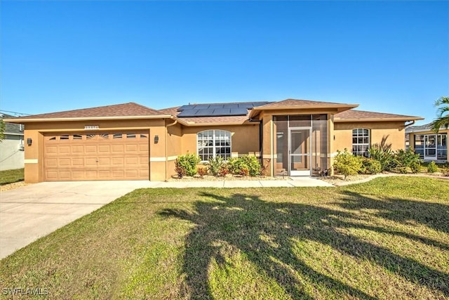 view of front of property featuring a sunroom, a garage, a front yard, and solar panels