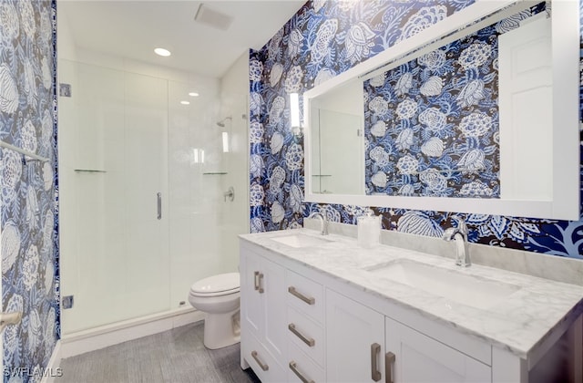 full bathroom with a stall shower, a sink, toilet, and wallpapered walls