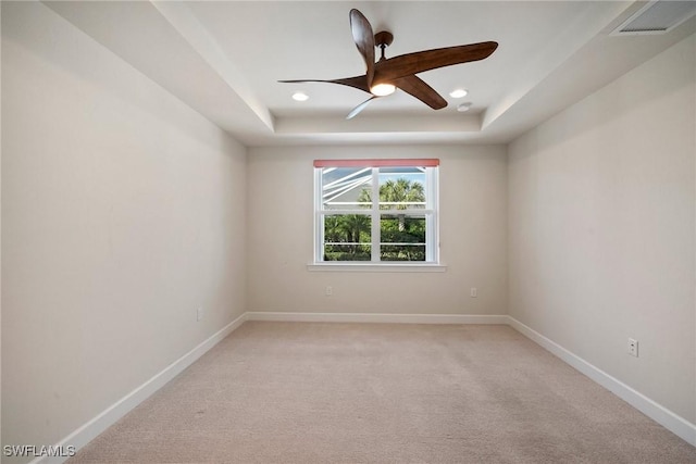 carpeted spare room featuring ceiling fan and a tray ceiling