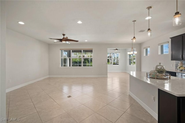 interior space with pendant lighting, ceiling fan with notable chandelier, light stone counters, and light tile patterned flooring