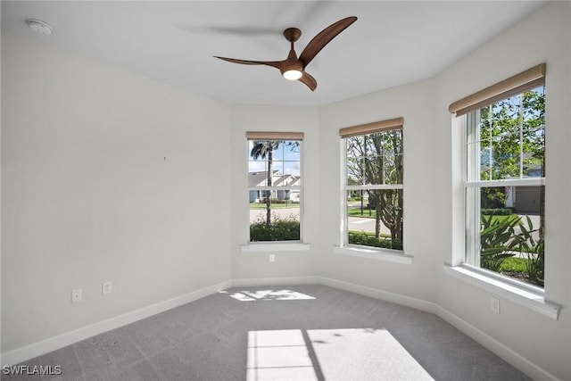 carpeted spare room featuring a wealth of natural light and ceiling fan