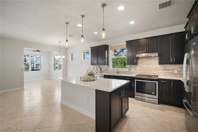 kitchen with pendant lighting, ceiling fan with notable chandelier, a center island, and appliances with stainless steel finishes