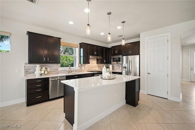 kitchen featuring a kitchen island, decorative light fixtures, decorative backsplash, light tile patterned floors, and appliances with stainless steel finishes