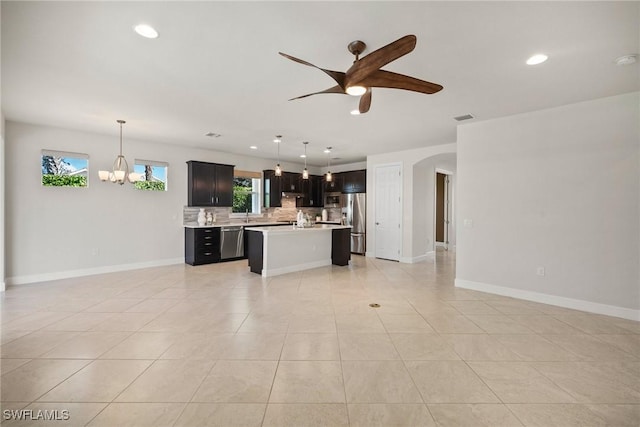 kitchen featuring a center island, backsplash, stainless steel appliances, and hanging light fixtures