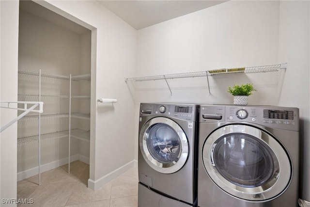 laundry area featuring washing machine and clothes dryer and light tile patterned floors