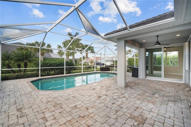 view of swimming pool with a patio area, ceiling fan, and glass enclosure