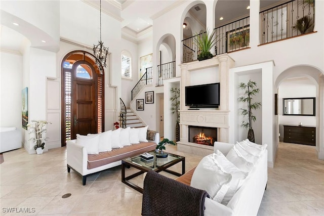 living room with a chandelier, a towering ceiling, and ornamental molding