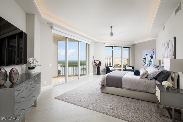 bedroom with ceiling fan, a wall of windows, a tray ceiling, access to outside, and a water view