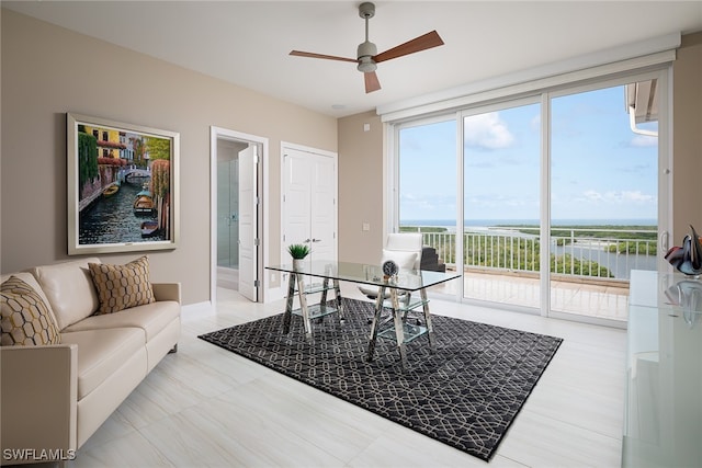 living room featuring expansive windows, ceiling fan, and a water view