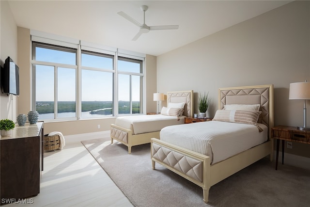 bedroom featuring ceiling fan and a water view