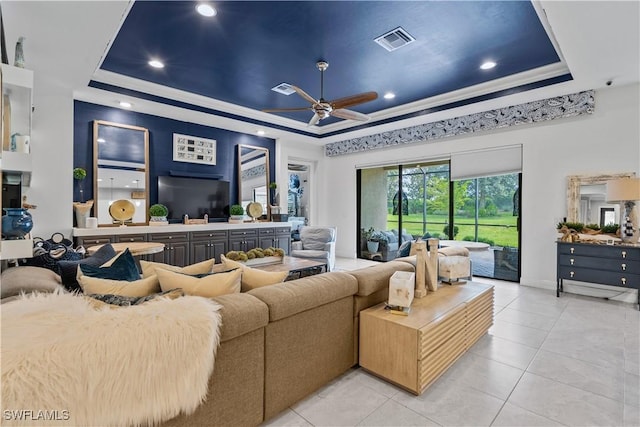 living room with ornamental molding, light tile patterned floors, ceiling fan, and a raised ceiling