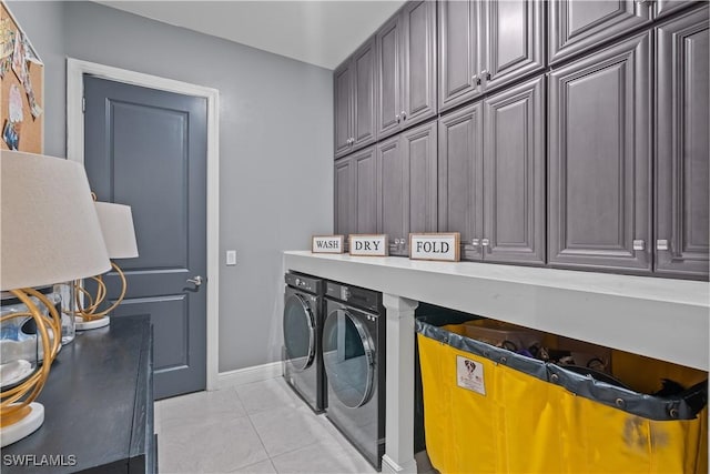 laundry area with washing machine and clothes dryer, light tile patterned floors, and cabinets