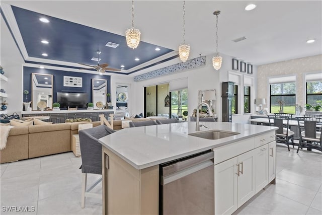 kitchen featuring dishwasher, white cabinetry, sink, a raised ceiling, and a center island with sink