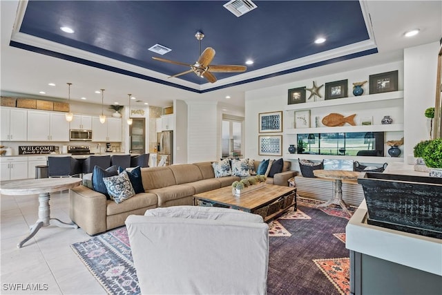 living room featuring light tile patterned flooring, ornamental molding, ceiling fan, and a raised ceiling