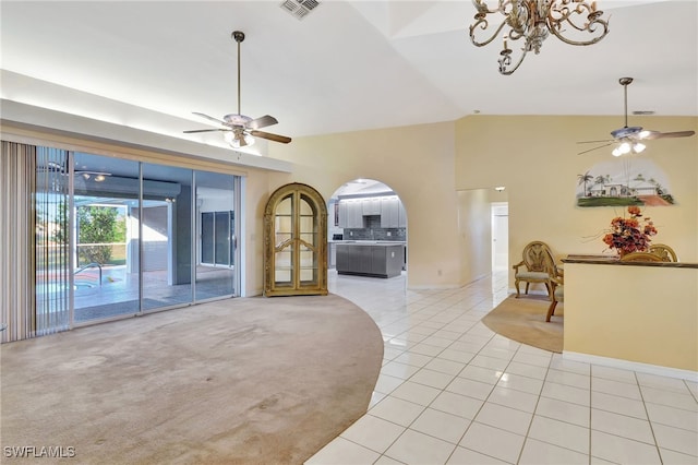 unfurnished living room with lofted ceiling, light tile patterned floors, and ceiling fan with notable chandelier